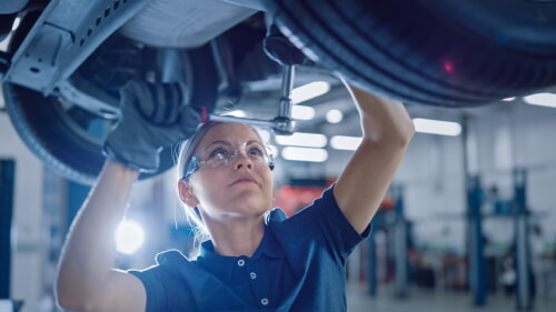female mechanic working on an automobile performing repair and maintenance services