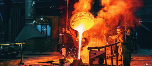 liquid metal poured into a container inside a foundry