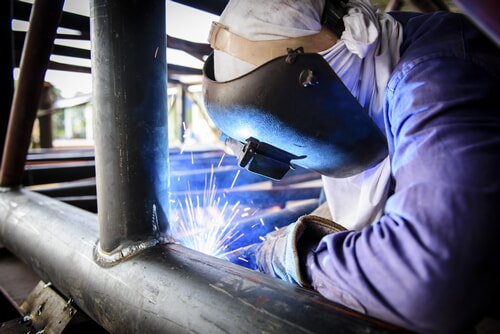 man welding a steel tubular structure