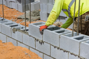 Masonry worker building a cement wall with blocks wearing safety equiptment