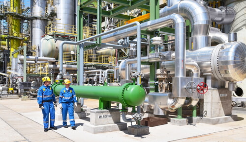 men working at oil refinery wearing proper PPE