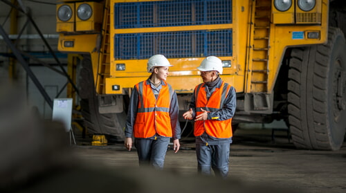 man and woman working with heavy equipment at a mine wearing PPE
