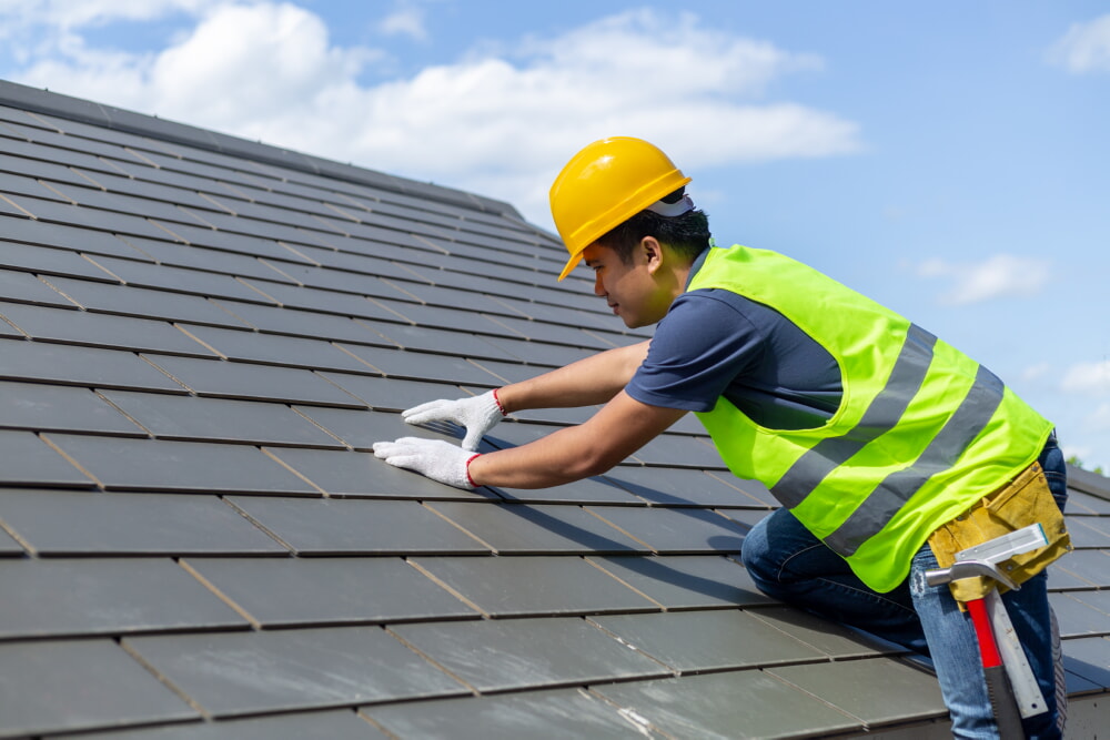 Roofer adjusting tiles on a new roof at a construction site