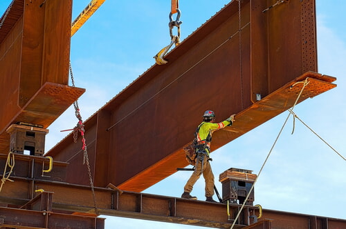 workers in the steel industry building a bridge while wearing proper PPE for their safety