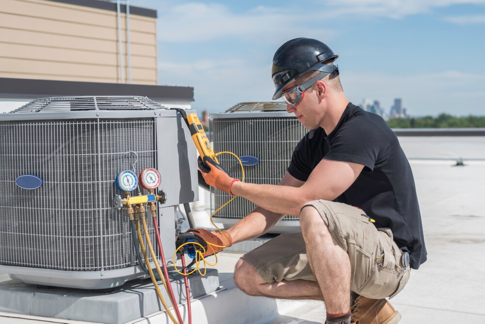 Worker servicing a commercial HVAC unit using safety equipment